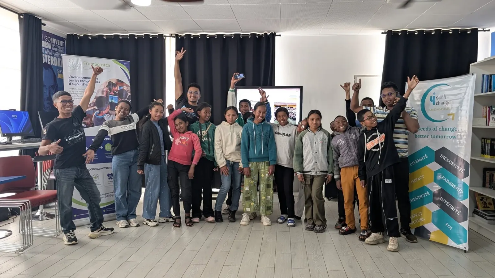 Un groupe de jeunes participants lève les bras à la fin d'une session de littératie numérique FromScratch.