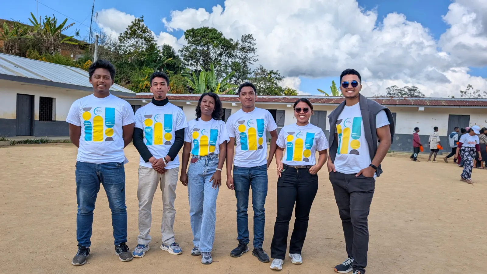 L'équipe Y4CM en t-shirts 'Seeds of change, better tomorrow' dans la cour d'une école.